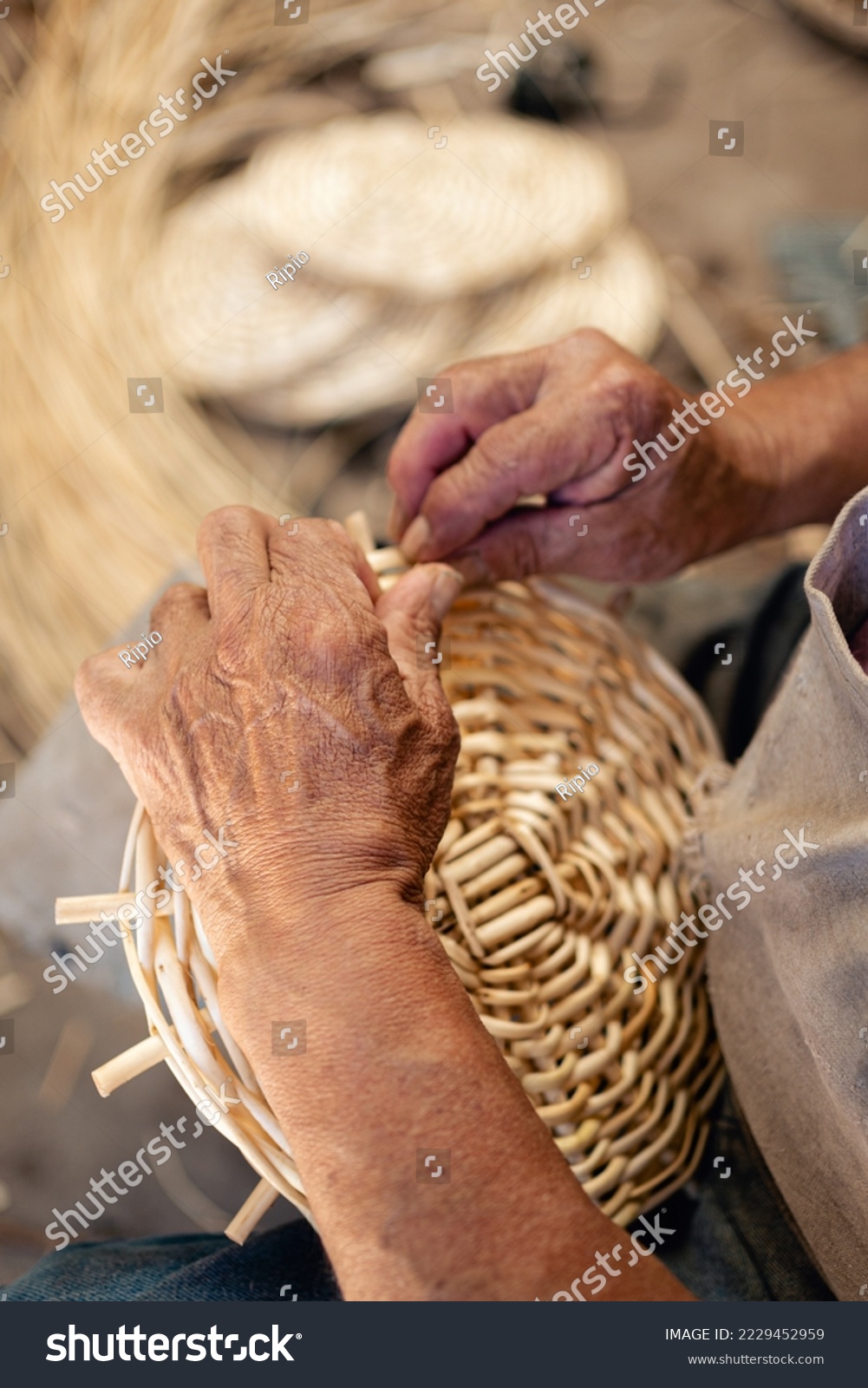 Close up caption of man hands weaving wicker for a craft basket. Vertical photography. South American culture and Tradition #2229452959
