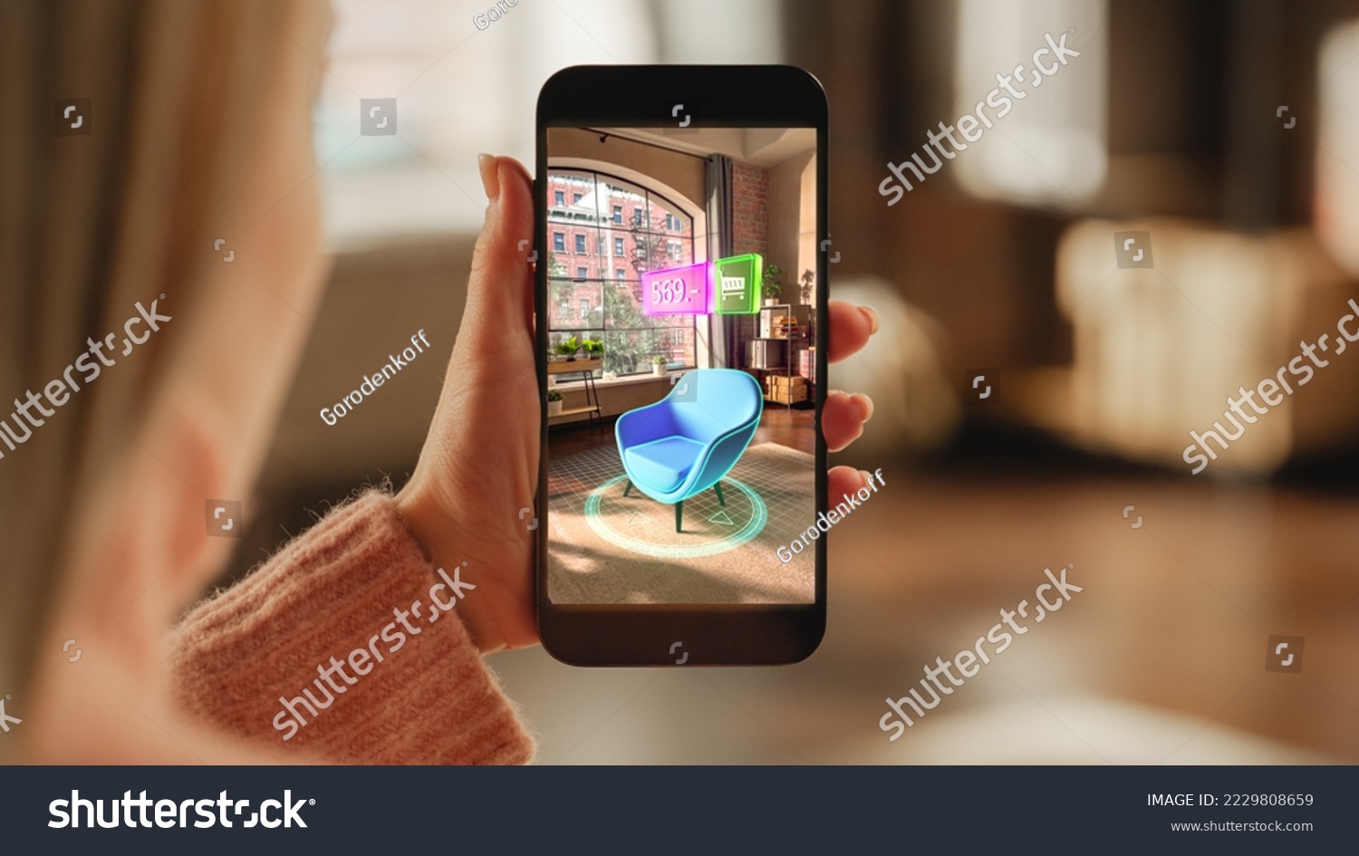 Over the Shoulder Footage of a Female Hand, Holding Smartphone with an Augmented Reality Display Showing a Chair. Woman Doing Online Shopping and Checking her Options In Live Situation In Distance #2229808659
