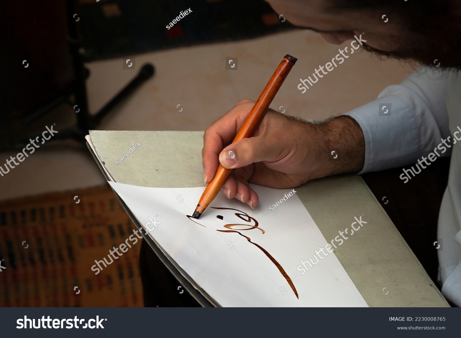 A calligrapher writing with pen and ink. man hands writing arabic calligraphy with ink. Arabic and Persian calligraphy. Writing Nastaliq calligraphy. Abstract and unclear writing. #2230008765
