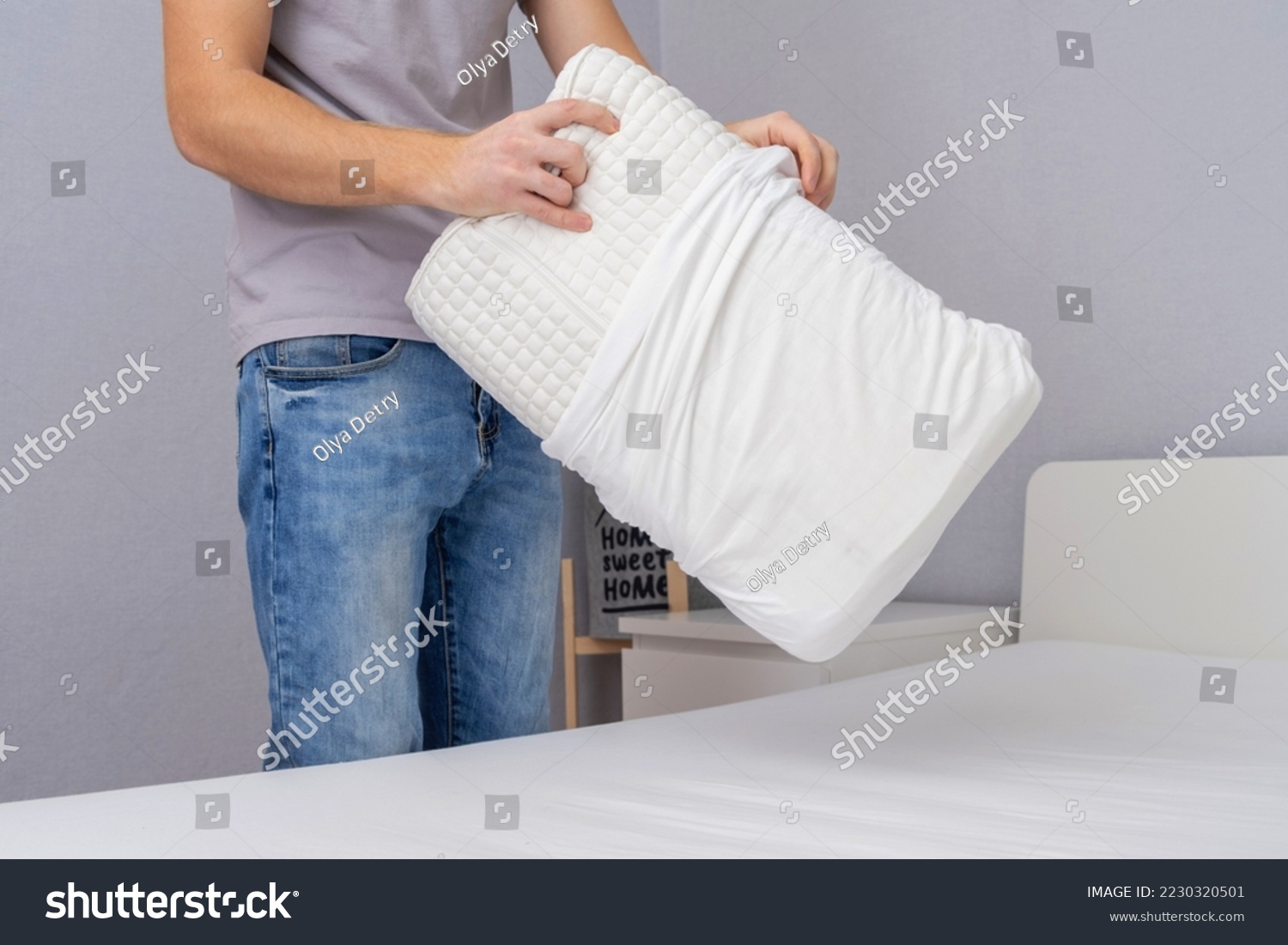 A man tucks an orthopedic pillow with a fresh bright white pillowcase. Making bed with fresh bed linen by white man. The day of change of bed linen. The day of washing bed linen in the laundry room. #2230320501
