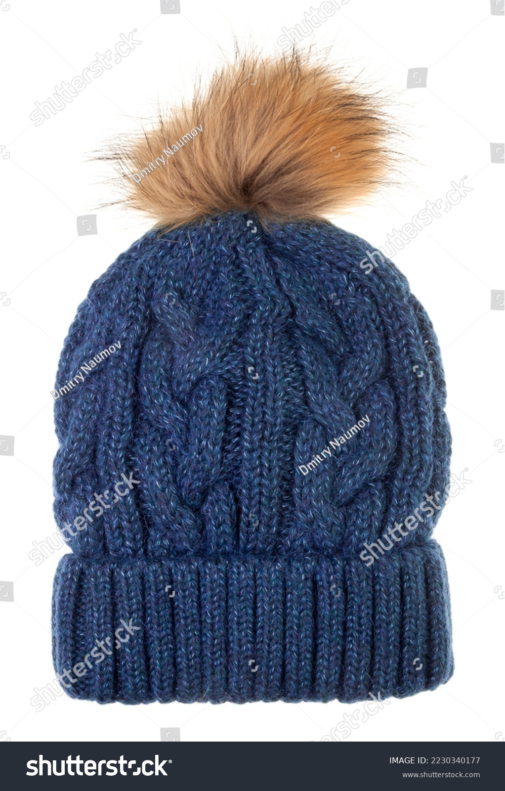 Blue woolly winter bobble hat decorated with cable knitting ornament isolated on white background. Handmade woolly cap with fake fur pompom on top #2230340177