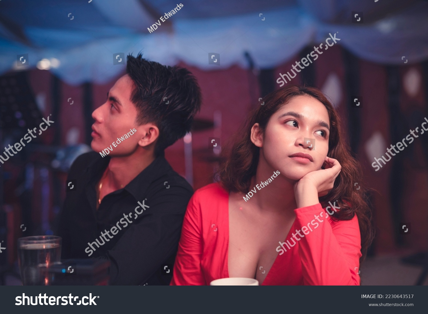 A couple having a date at an elegant restaurant sits back to back and ignores each other as they are having an argument. A lady is upset with her insensitive boyfriend. Waiting for the night to end. #2230643517