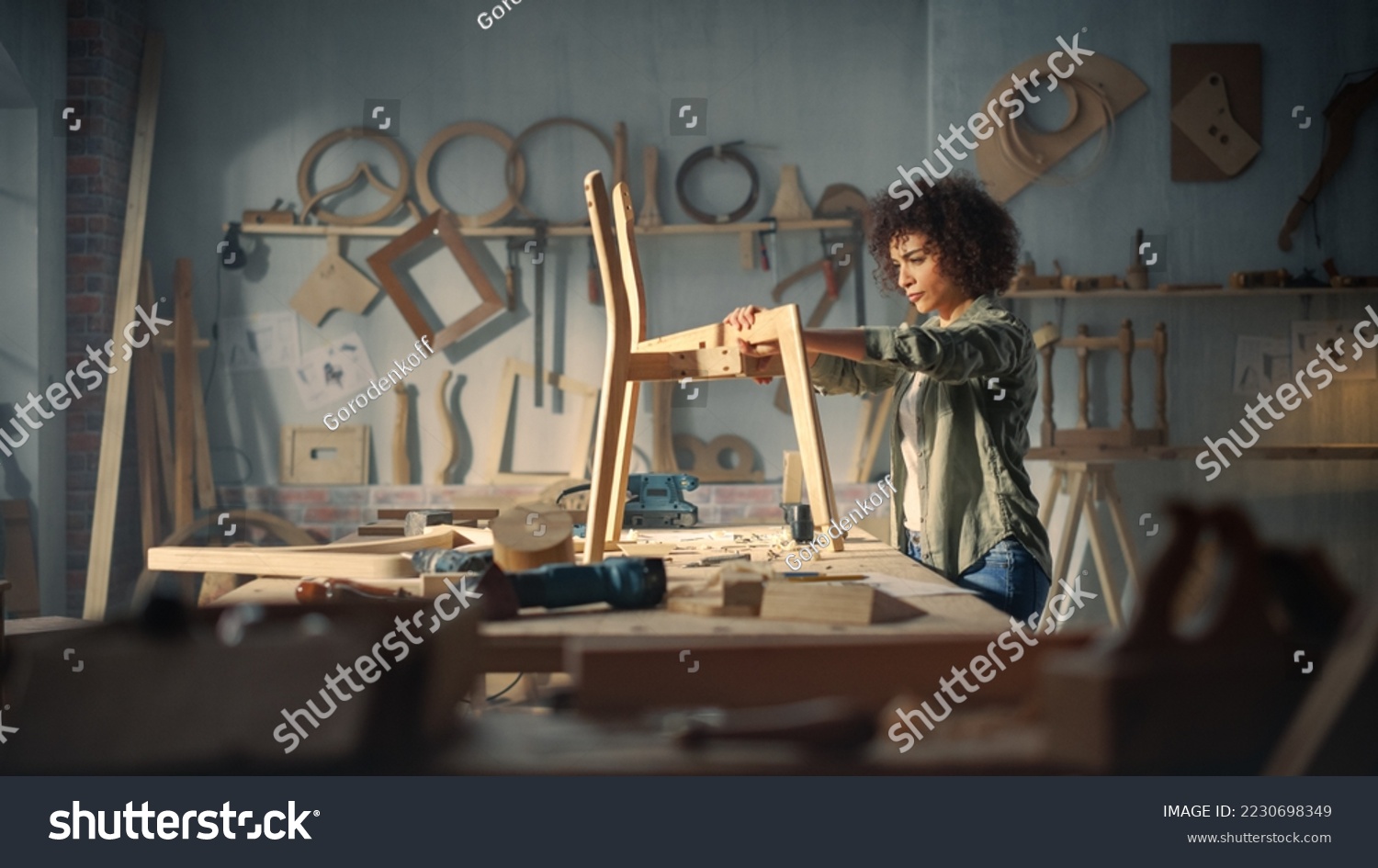 Female Artisan Furniture Designer Marking Out Dimensions on a Blueprint and Starting to Assemble a Wooden Chair. Multiethnic Black Carpenter Working in a Studio #2230698349
