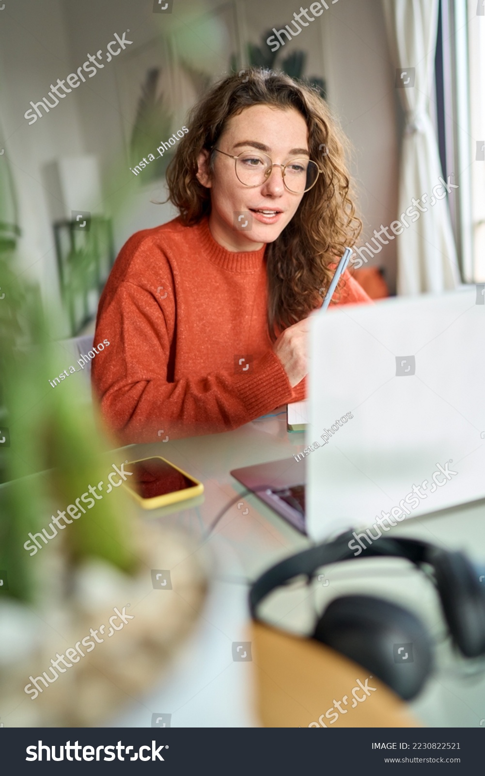 Young woman, female student or worker using laptop elearning or remote working at home office looking at computer watching webinar or having virtual meeting communicating by video call. Vertical. #2230822521