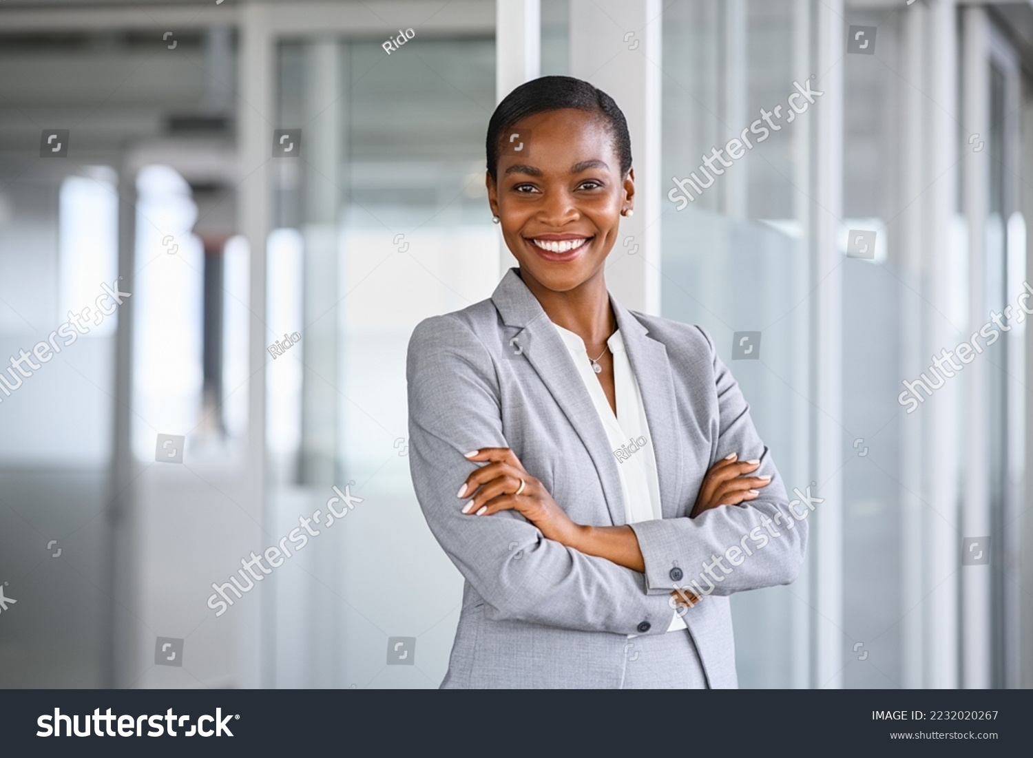 Portrait of mid adult successful black mature woman looking at camera with arms crossed. Smiling african american business woman standing in new office with copy space. Portrait of mature woman. #2232020267