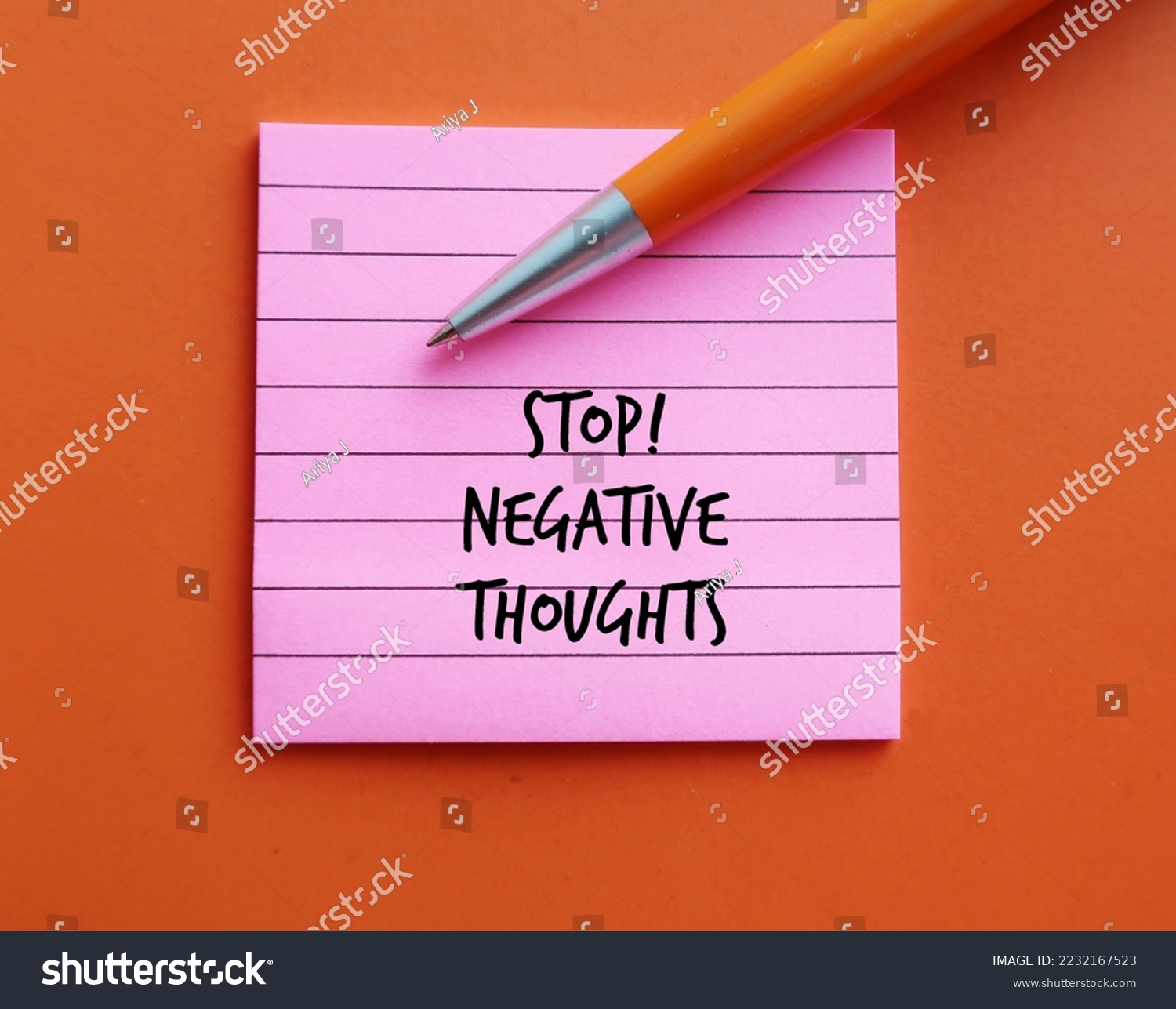 Pink note on orange background with pen written STOP NEGATIVE THOUGHTS, means stop mind fro attracting negative life experiences, overcome and remove negative thinking  #2232167523