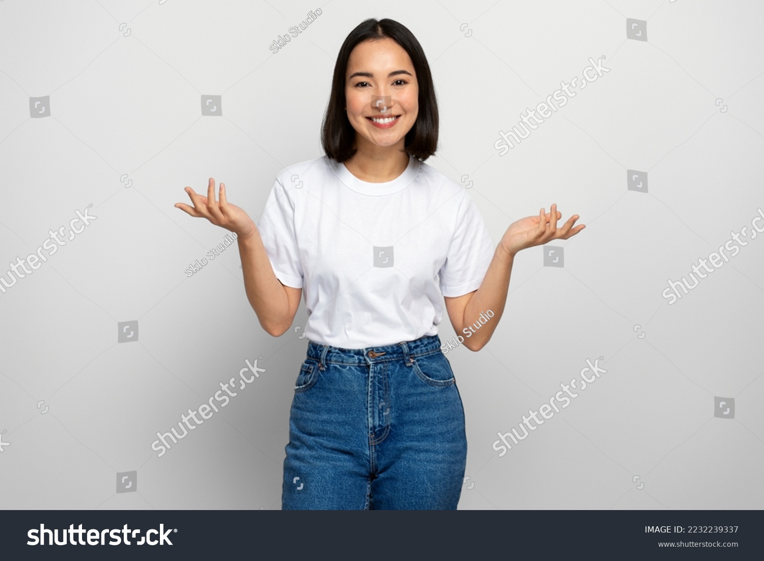 Uncertain positive woman with raised arms, dont know what to do. Indoor studio shot isolated on white background #2232239337