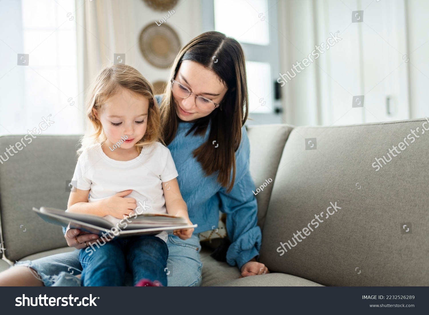 A happy kid sitting on sofa with babysitter holding book #2232526289