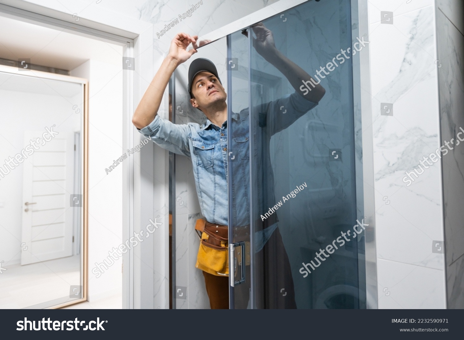 Handyman installing glass cabinet in bathroom. #2232590971