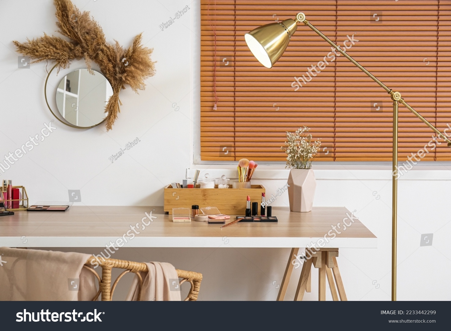 Box with makeup brushes, decorative cosmetics and flowers in vase on table near light wall #2233442299