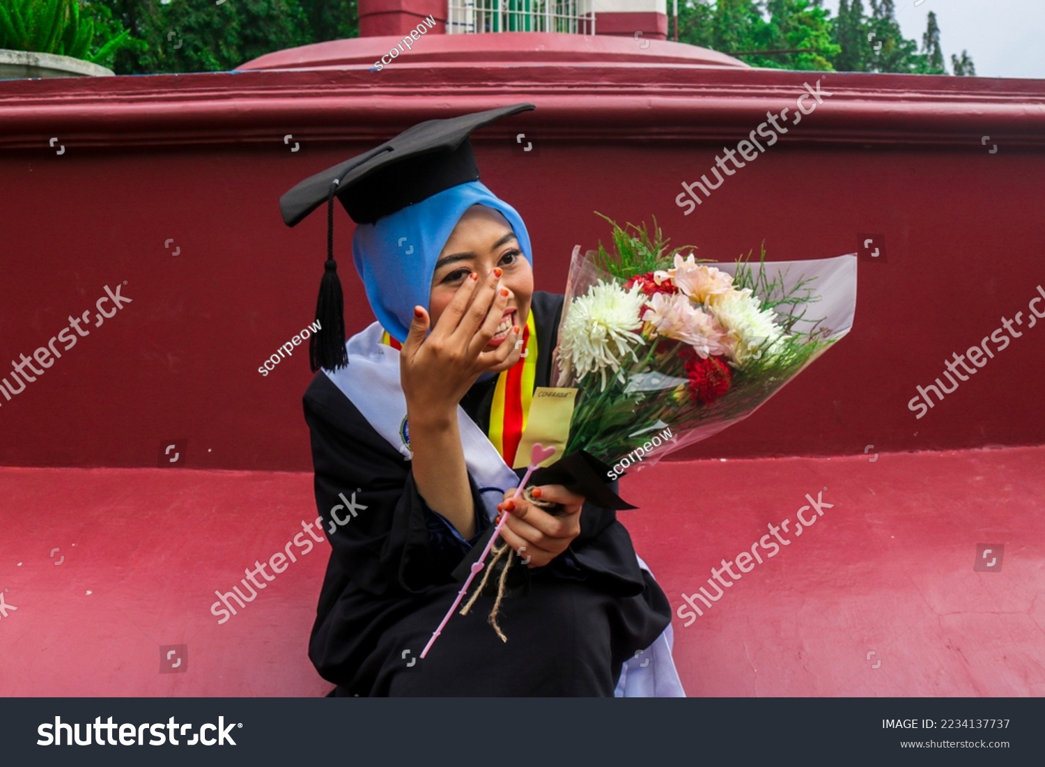 Woman crying tears of joy on her graduation day. Girl holding bouquet of flowers crying on graduation day. Graduation Day at Yogyakarta State University #2234137737
