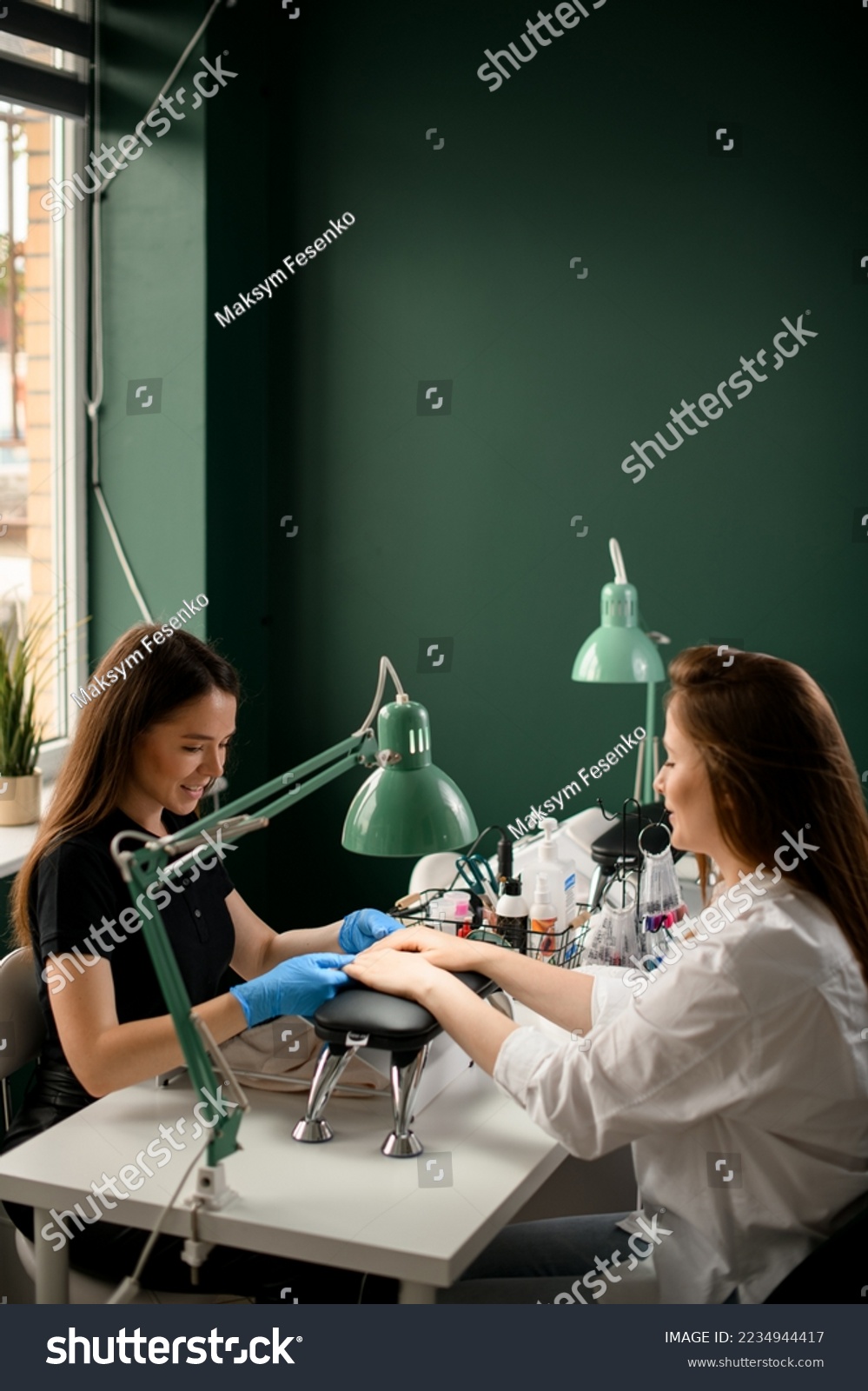 Handsome young woman manicurist doing manicure for female client. Manicure service. In professional beauty salon #2234944417