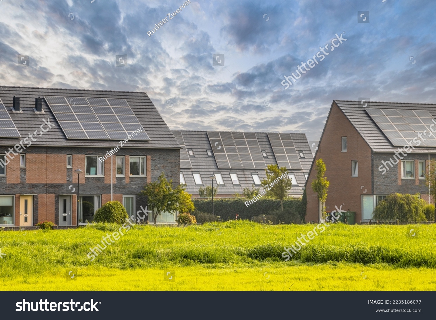 Row of modern family houses in contemporary street. New ecological neighborhood with solar panels. Small  gardens and private parking places. Street view in Heerhugowaard, Netherlands. #2235186077