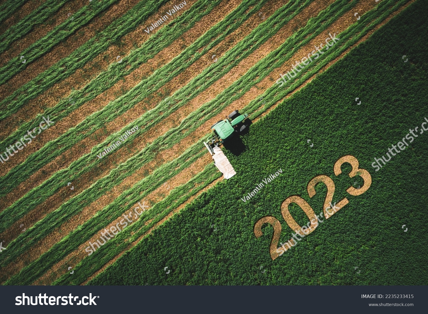 2023 Happy New year concept for agriculture, business, goals, success and new start banner. Industrial tractor on a green field. #2235233415