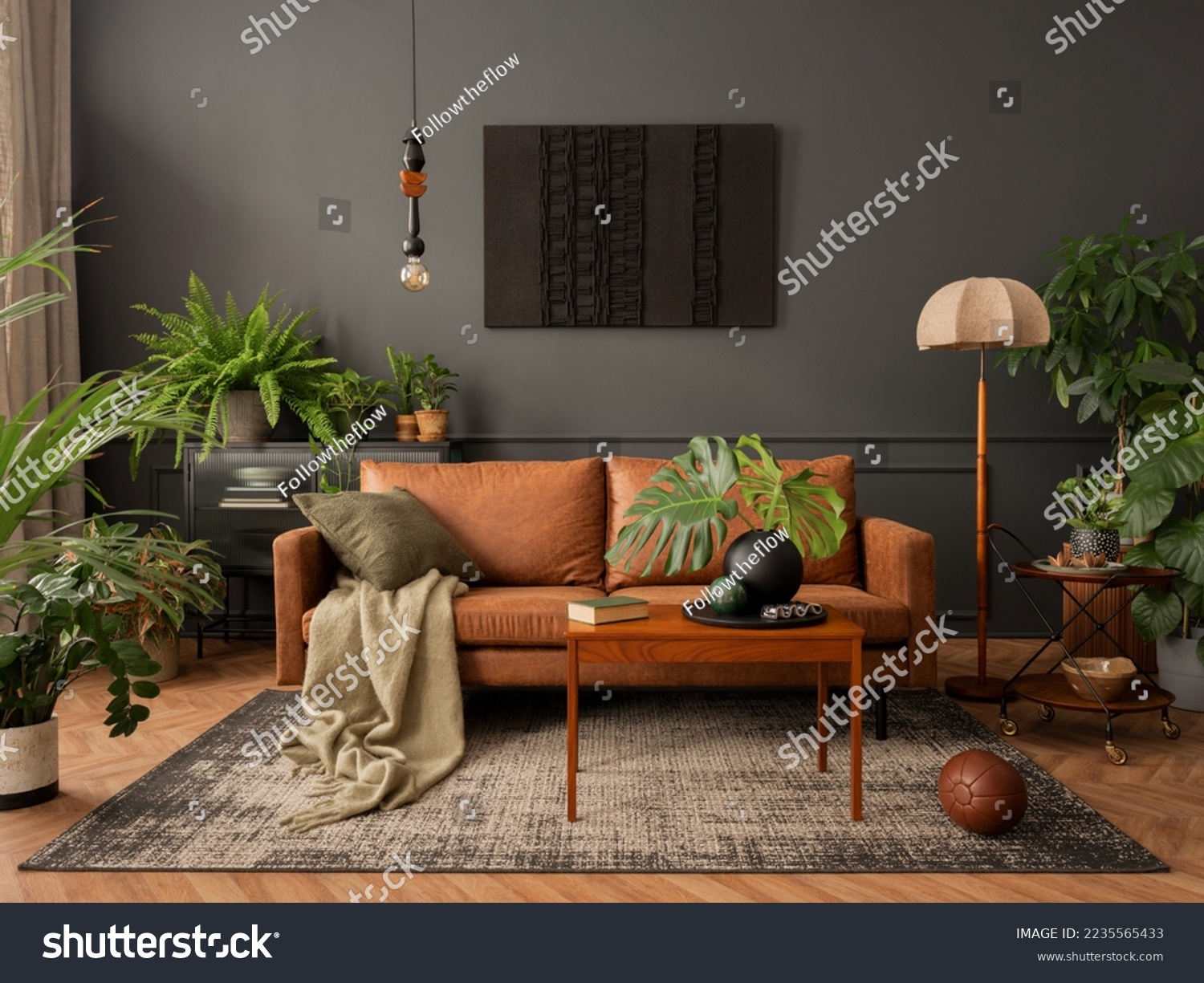Interior design of living room interior with mock up poster frame, brown sofa, plants, wooden coffee table, lamp, ball, stylish rug, plaid, pillows and personal accessories. Home decor. Template.  #2235565433