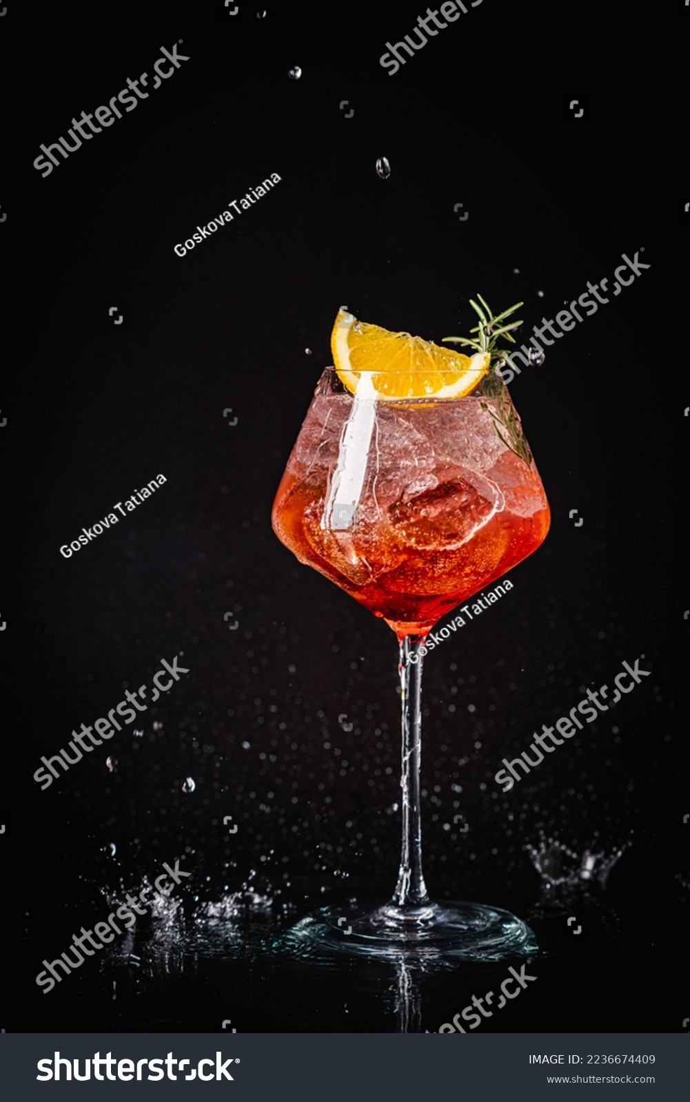 Aperol spritz cocktail in a glass with ice and orange on a black background #2236674409