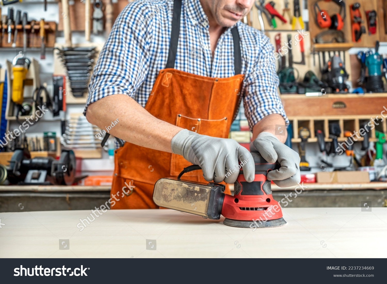 CARPENTER IN WORKSHOP WORKING WOOD WITH AN ORBITAL SANDER. SMALL BUSINESSES AND SELF EMPLOYED. DIY CONCEPT. #2237234669