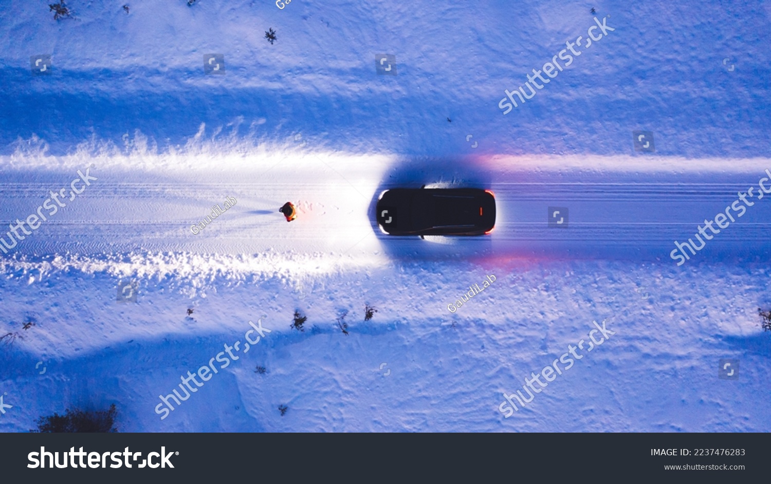 Aerial top view of car on rural area road while headlights are on in winter darkness, bird's eye view of suv vehicle in snowy north lands. Person standing front automobile which lighting the way #2237476283