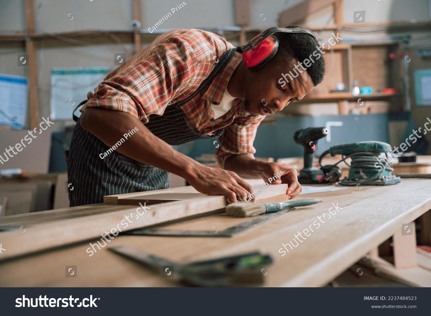 African carpenter measuring wood and timber with electric tools #2237484523