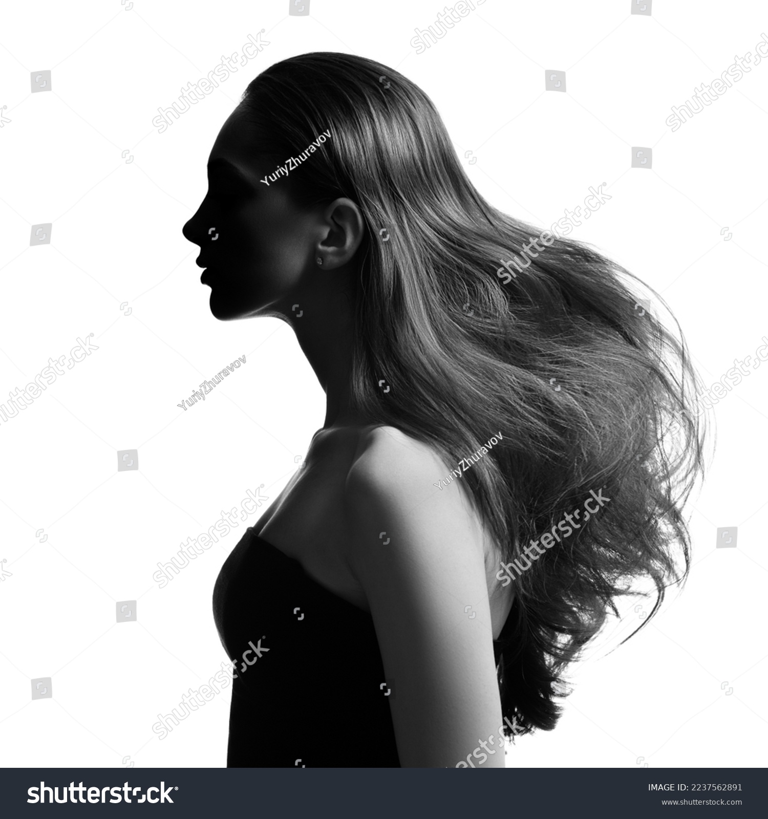 Portrait of a brunette girl with voluminous wavy hair. Black and white image. Side view. #2237562891