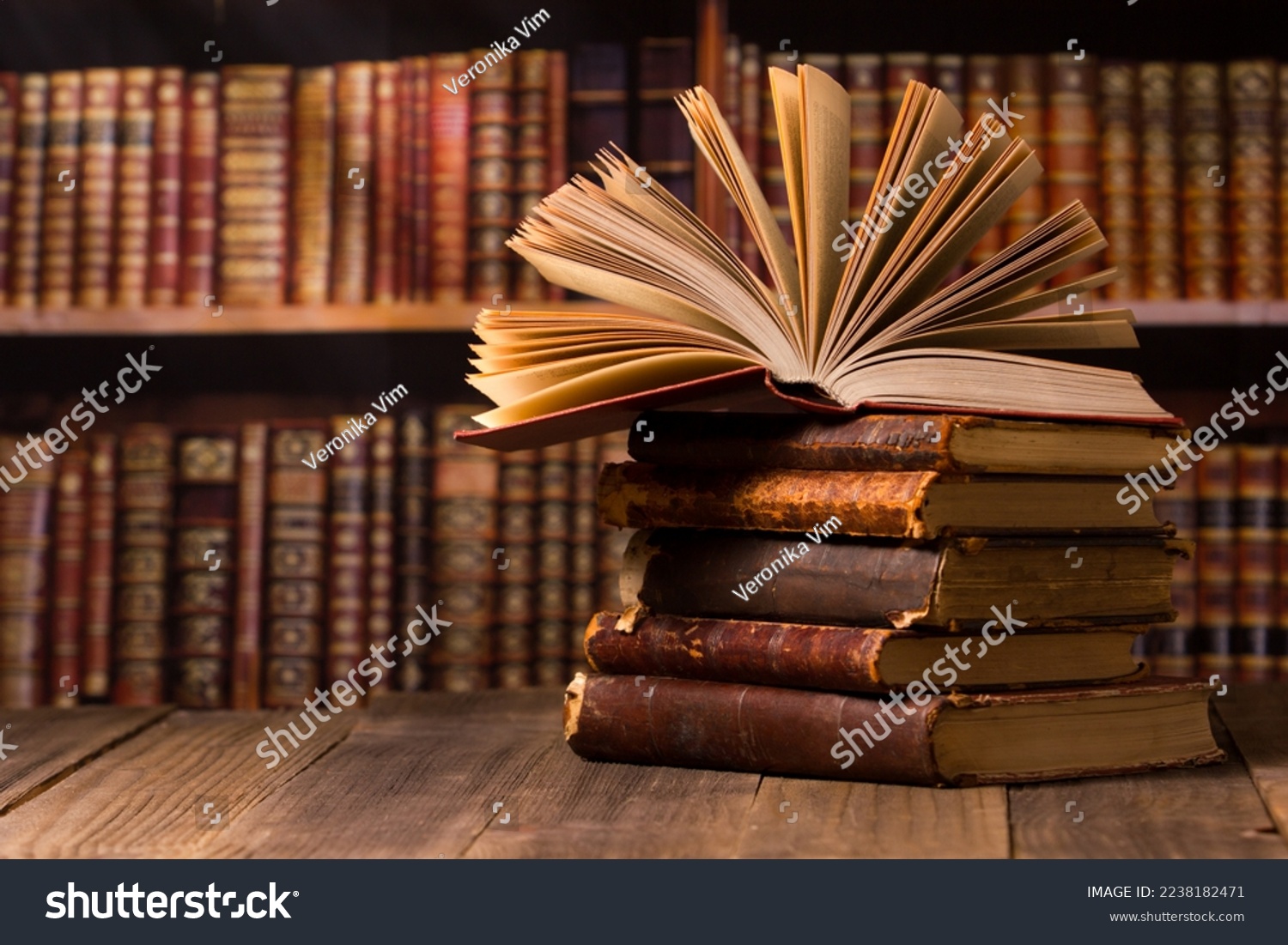 Composition with vintage old hardback books, diary, fanned pages on wooden deck table and red background. Books stacking. Back to school. Copy Space. Education background.	 #2238182471