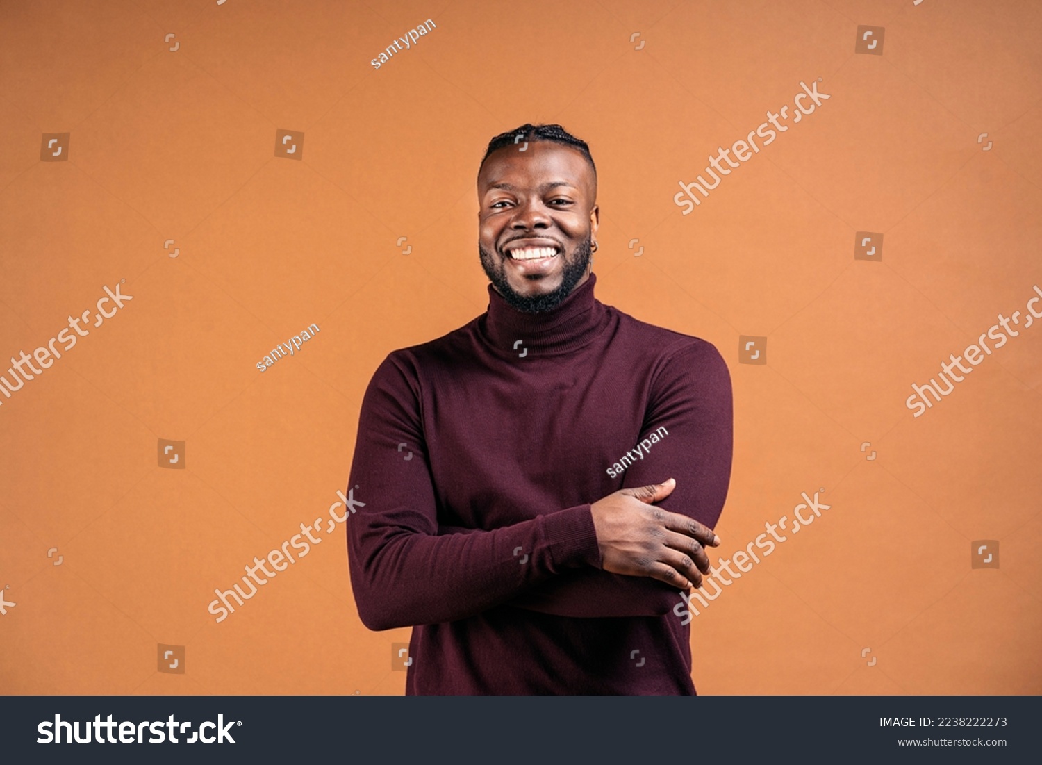 Cheerful black man wearing black leather jacket smiling in studio shot and looking at camera against brown background. #2238222273
