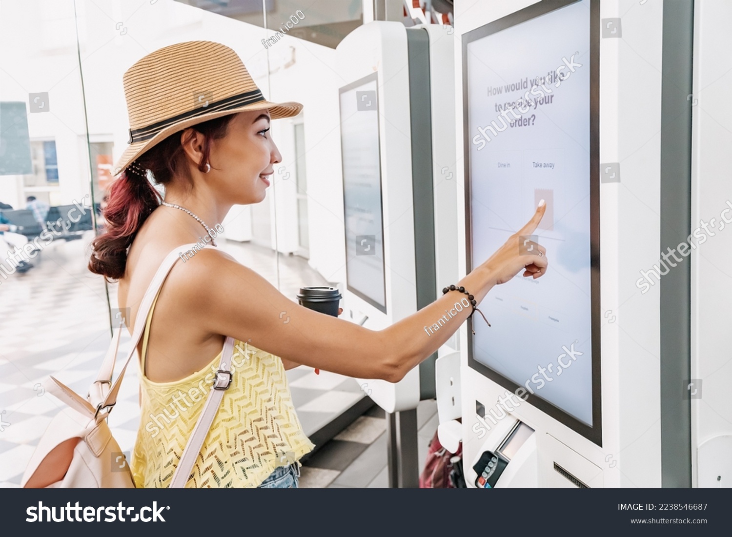 A female customer uses a touchscreen terminal or self-service kiosk to order at a fast food restaurant. Automated machine and electronic payment #2238546687