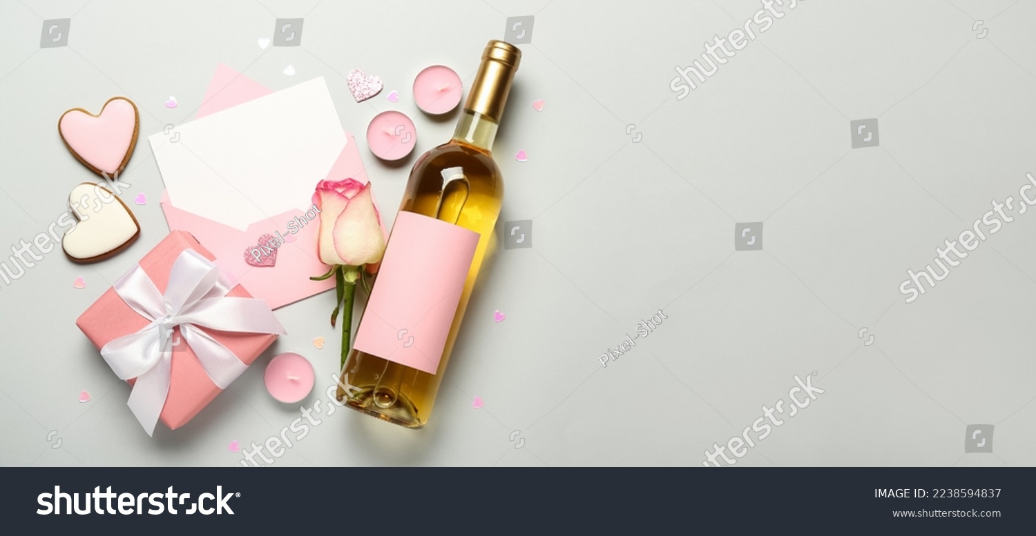 Blank letter, rose, bottle of wine, cookies, candles and gift on light background with space for text. Valentine's Day celebration #2238594837