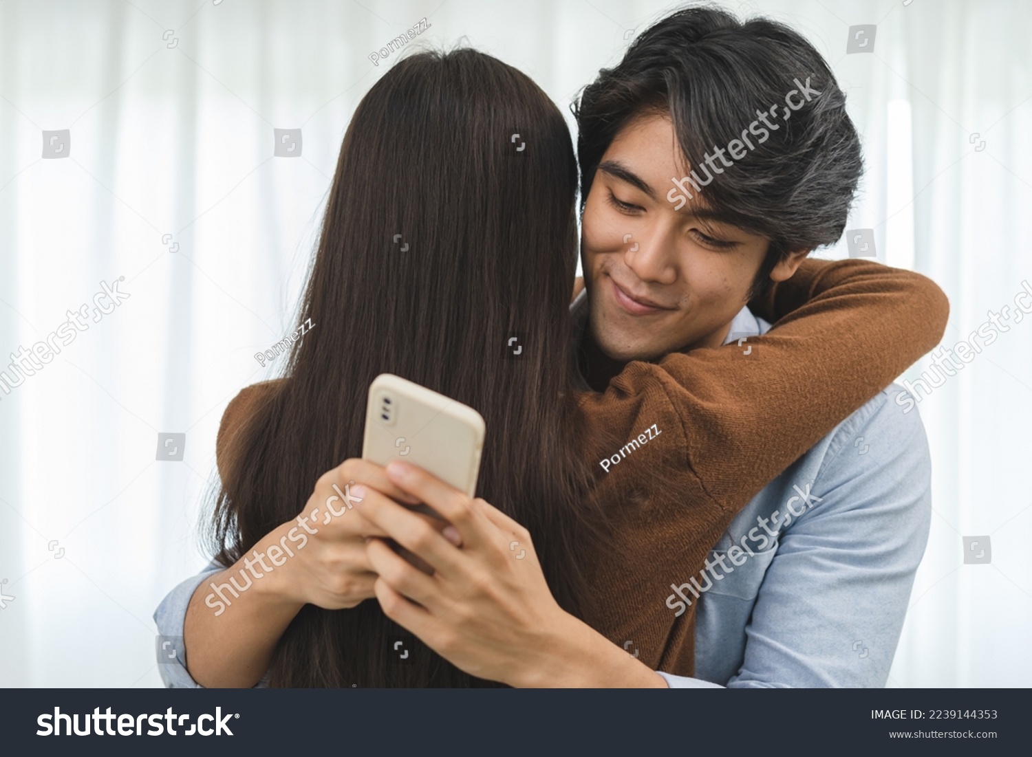 Cheating on girlfriends concept, unfaithful Asian man looking at mobile phone text during embracing with his lover #2239144353