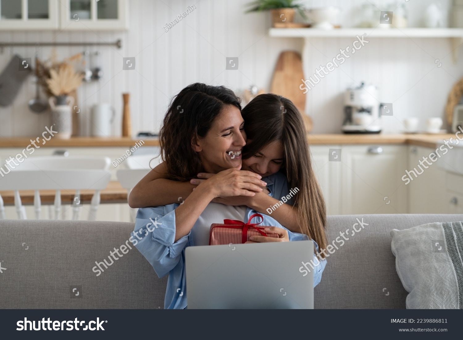 Little girl daughter hugging embracing happy beloved mother with love and tenderness while celebrating special occasion together at home, child wishing happy birthday to mom, greeting with Mothers Day #2239886811
