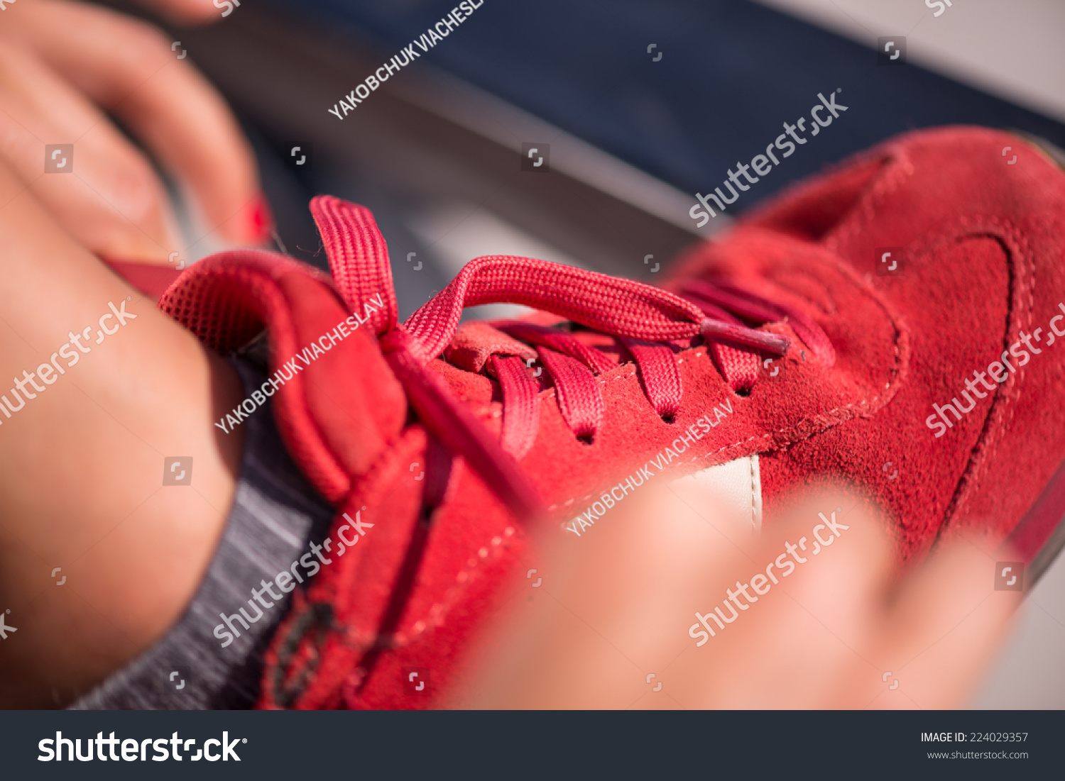 Selective focus on the legs of the woman wearing red jogging shoes putting right at it #224029357