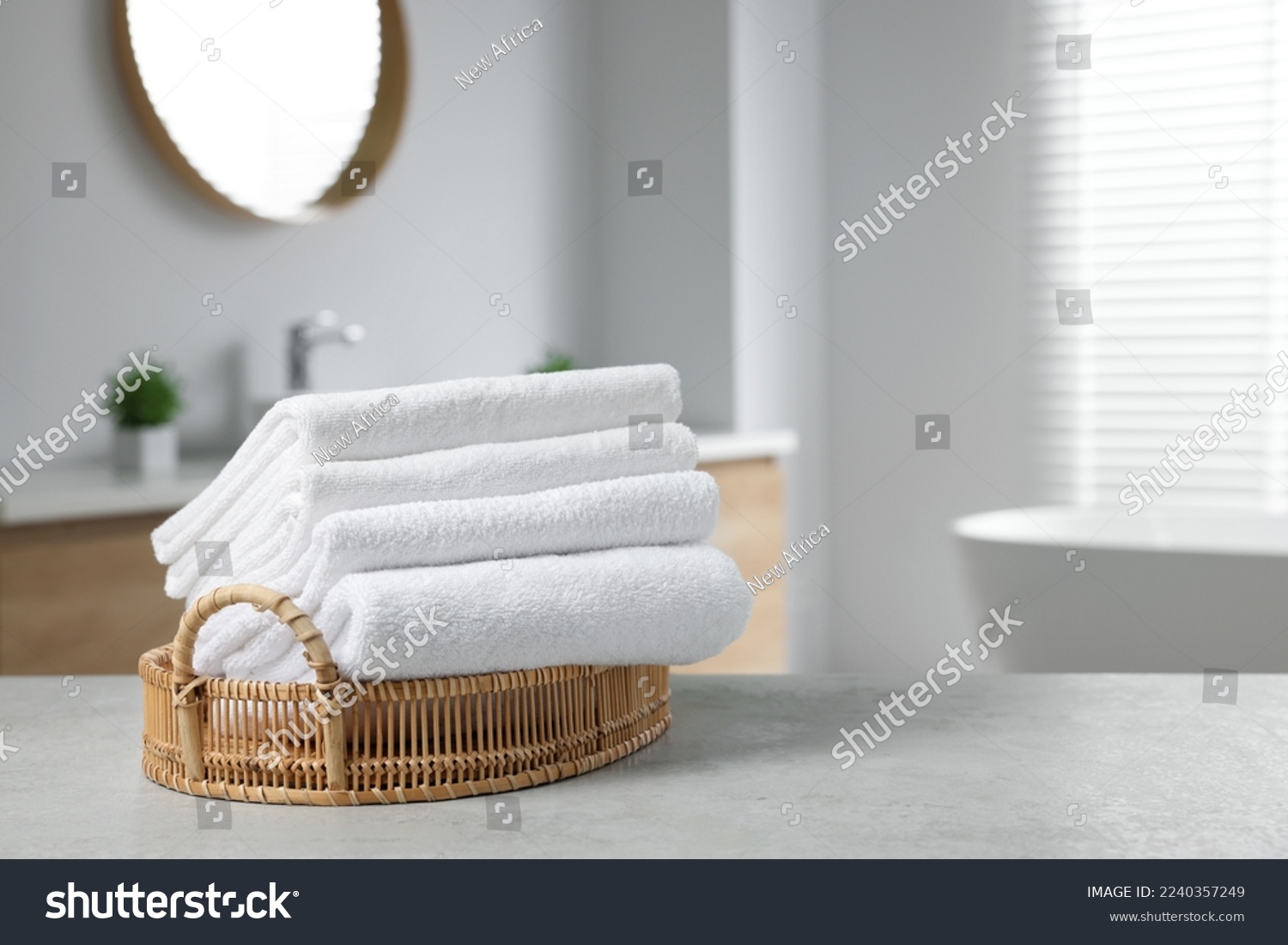 Wicker basket with white towels on table in bathroom. Space for text #2240357249