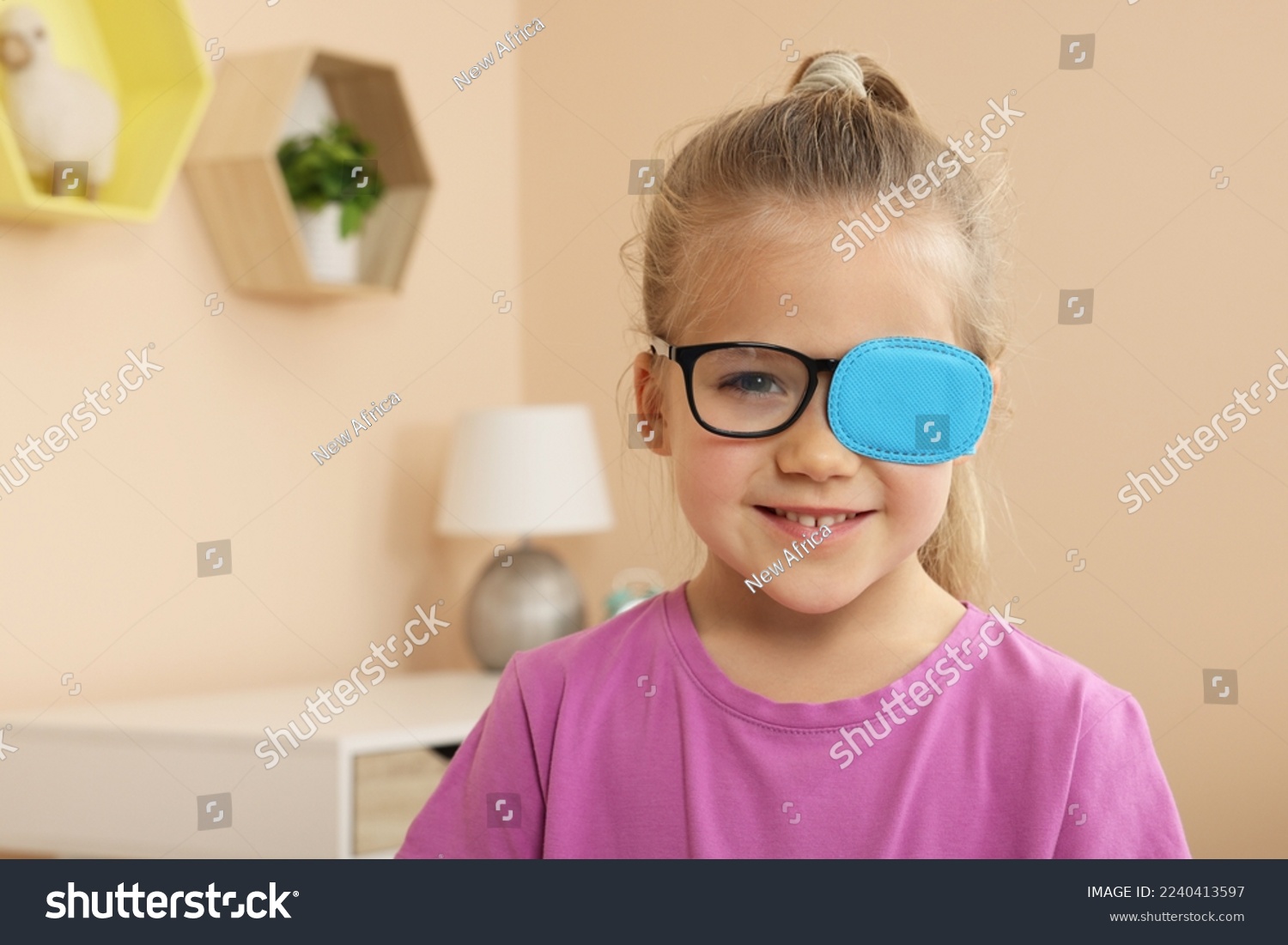Girl with eye patch on glasses in room, space for text. Strabismus treatment #2240413597