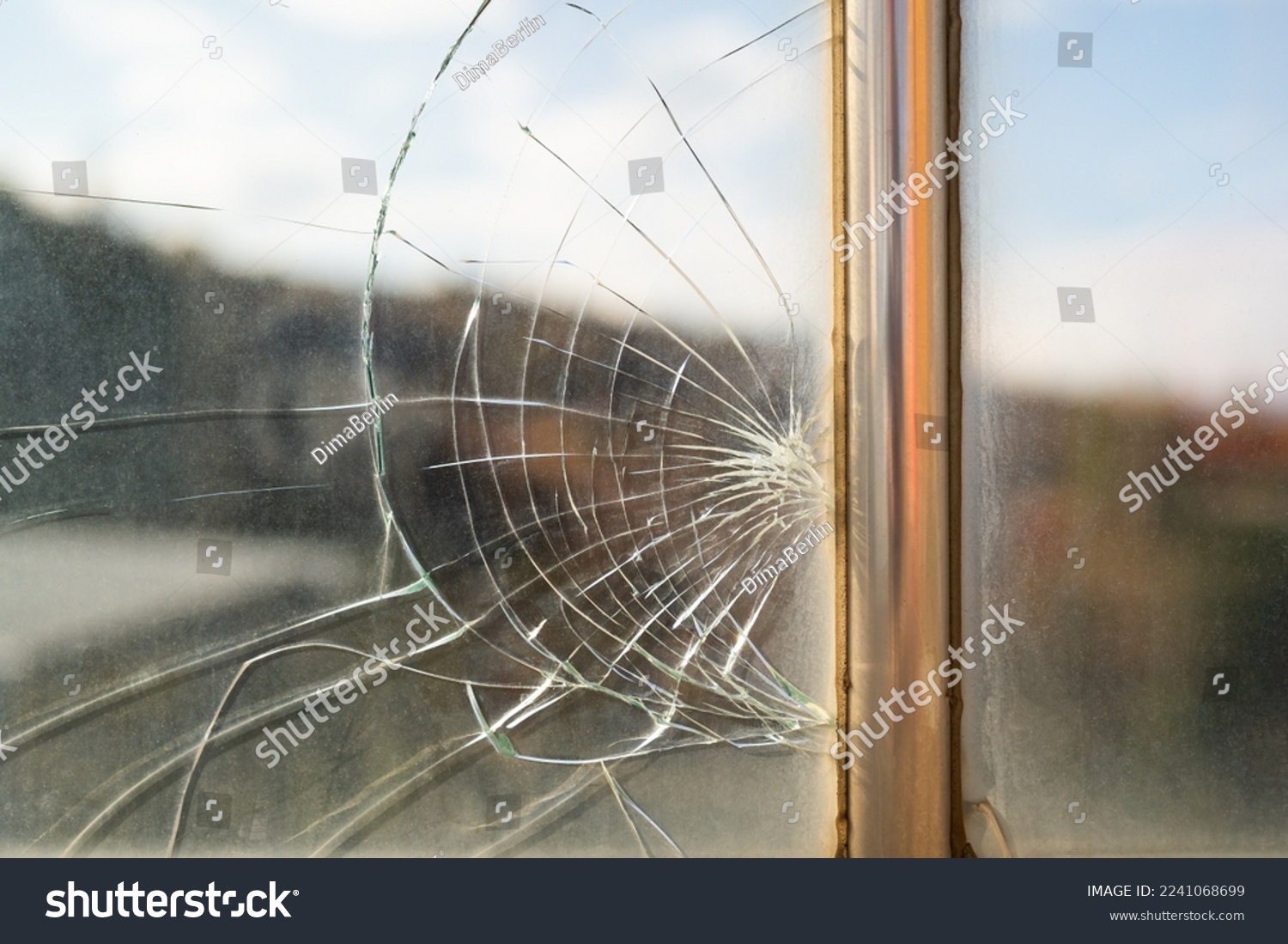Dirty broken glass with cracks from stone hit or beak from bird flying near creation. Unwashed window with view of picturesque nature with metal partition and traces of breakage needs to be replaced  #2241068699