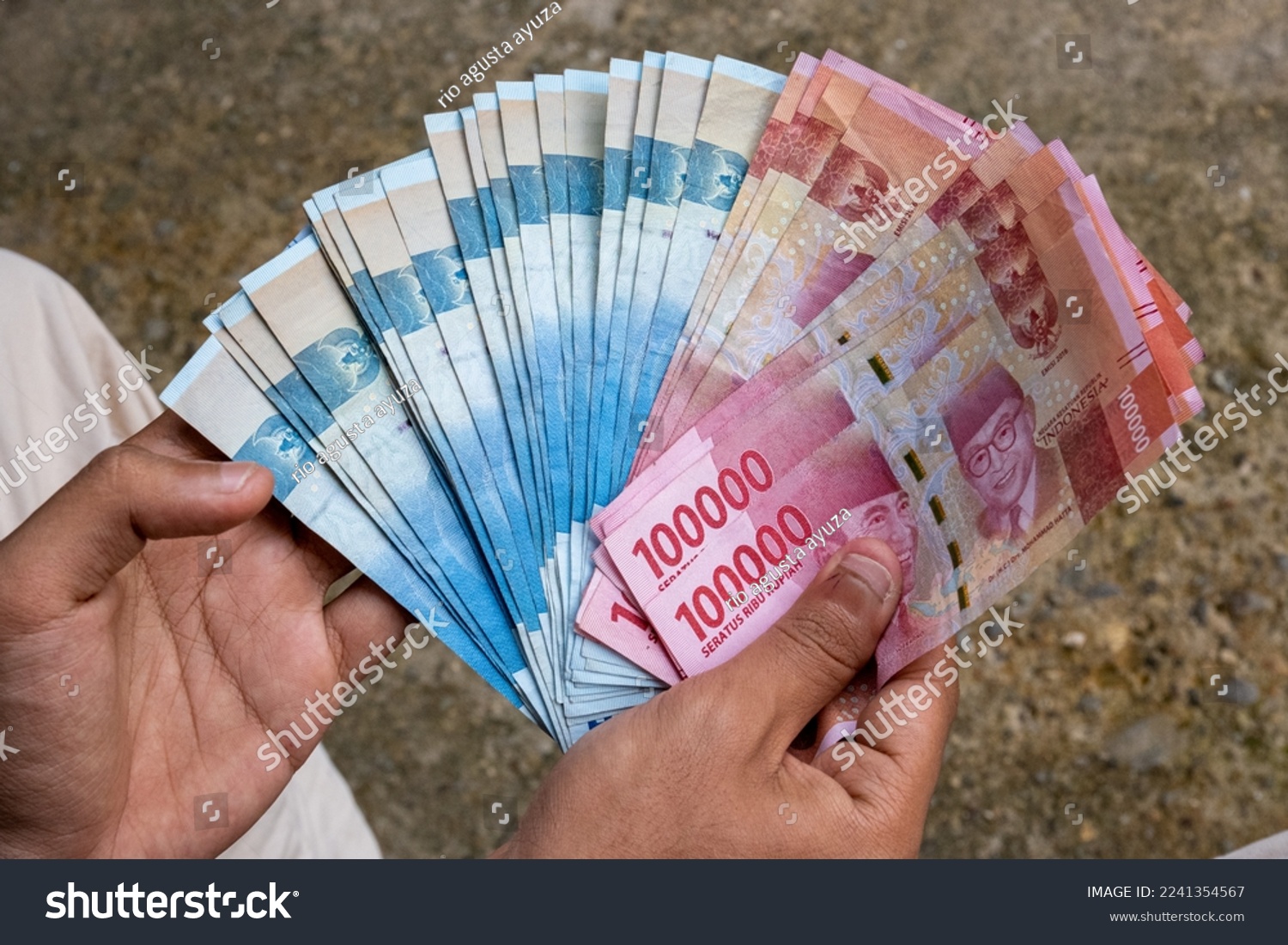 man showing Indonesian rupiah banknotes #2241354567