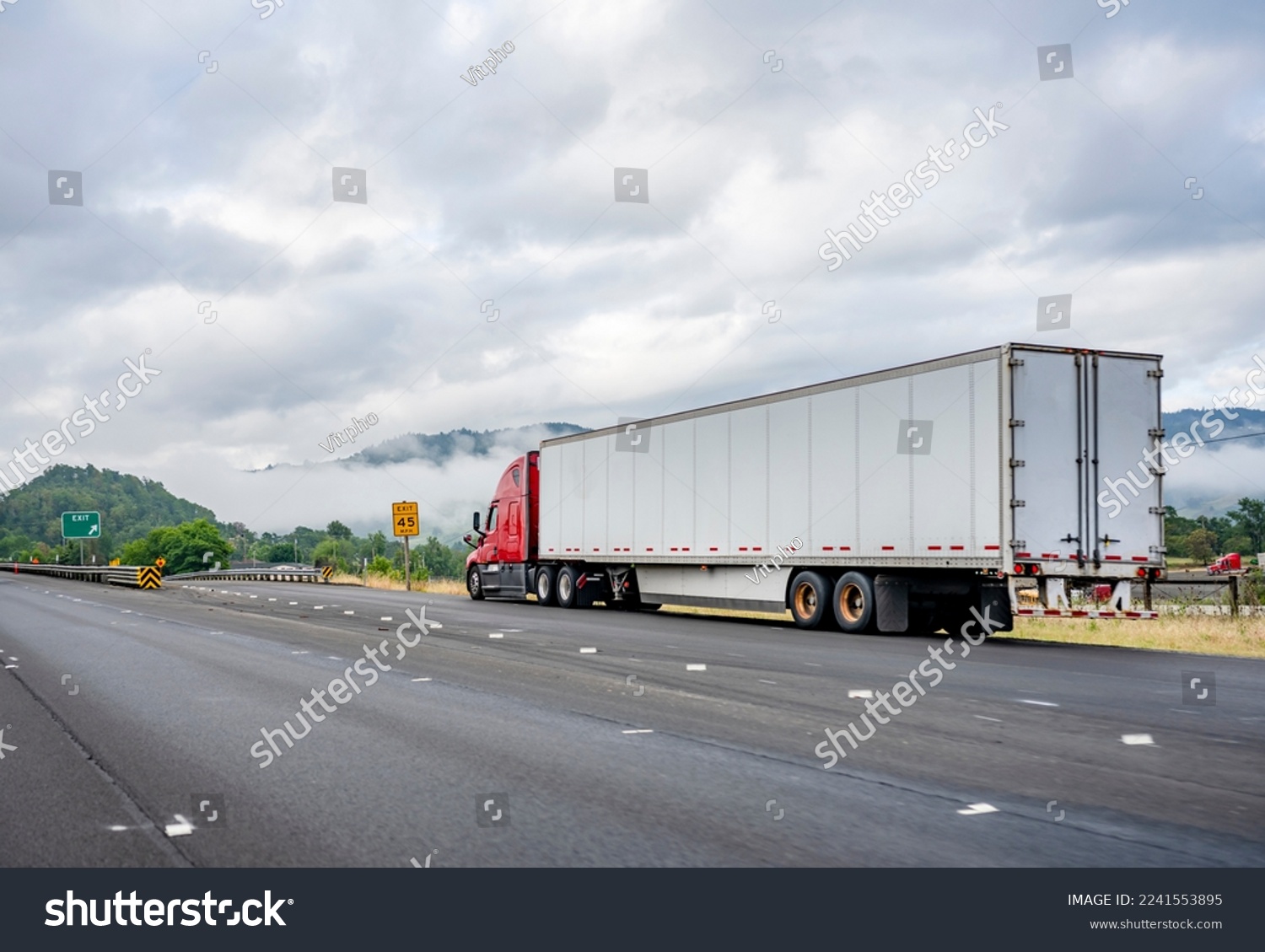Bright red industrial long haul big rig semi truck with dry van semi trailer stands on the side of the road having made a planned stop for a break according to schedule of movement along the log book #2241553895