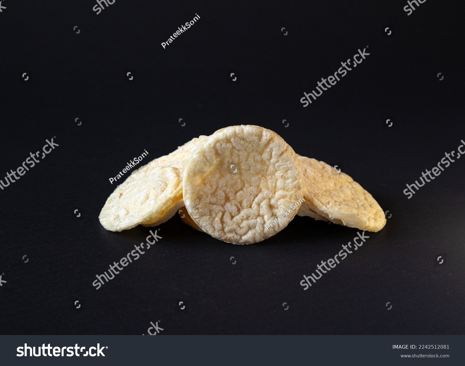 Puffed Potato Chips, Stacked on a plain black background with shadow, healthy potato snack.Puffed chis  #2242512081
