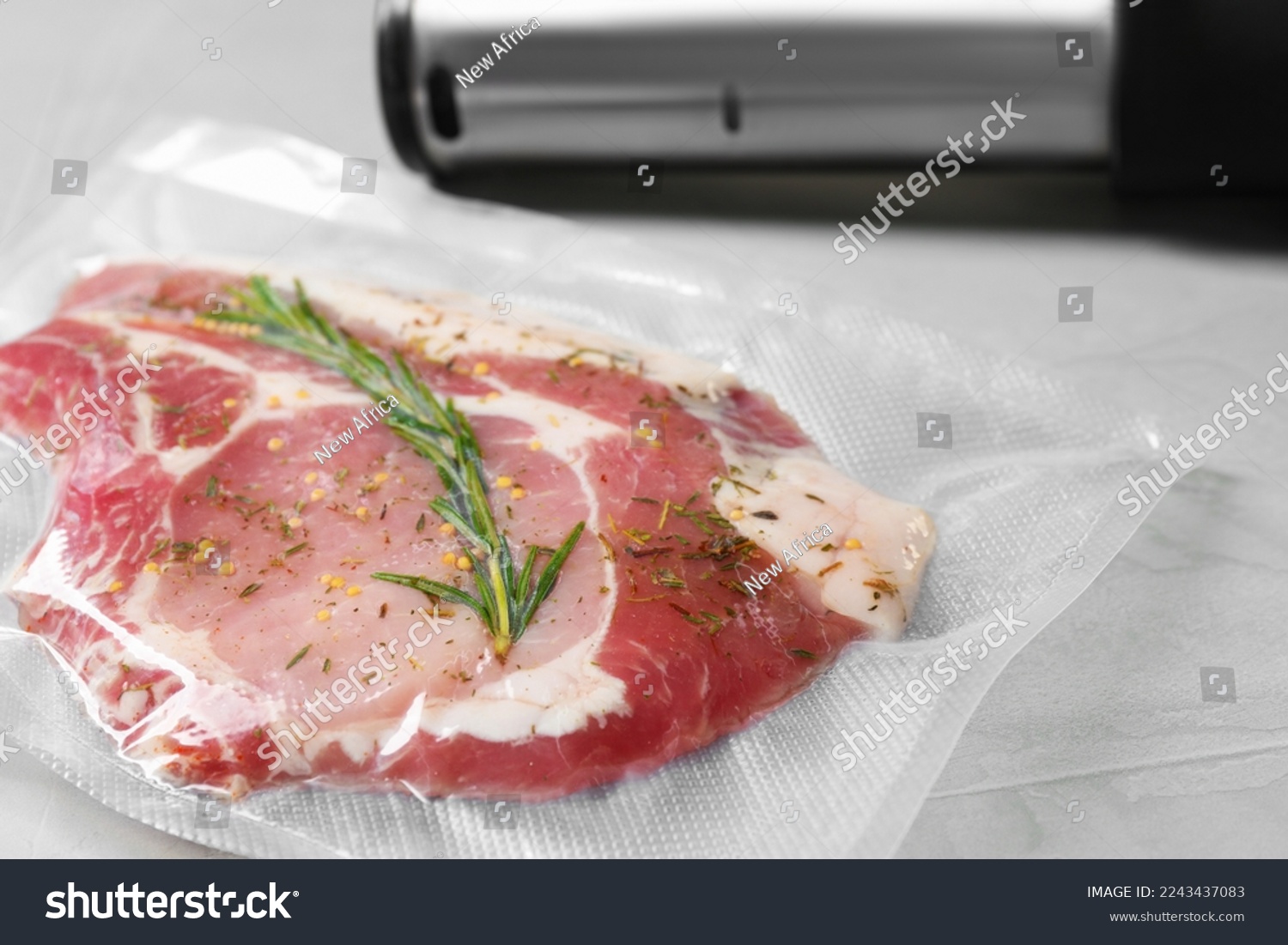 Sealer for vacuum packing with plastic bag of meat on light grey table, closeup #2243437083