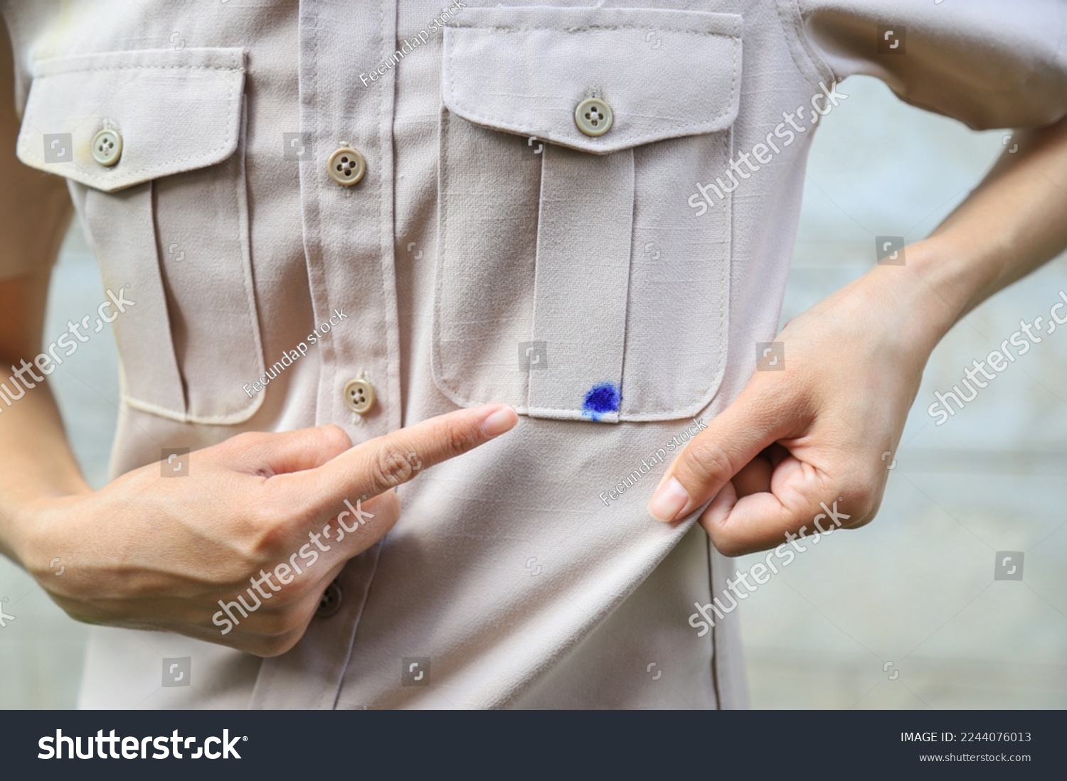 Hand showing dirty blue ink stain on shirt from accident in using pen in daily life. selective focus. stain for cleaning concept. #2244076013