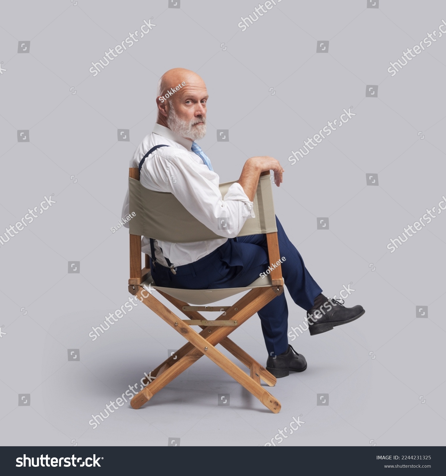 Confident film director sitting on the director's chair and looking at camera: video production, filmmaking and film industry concept #2244231325