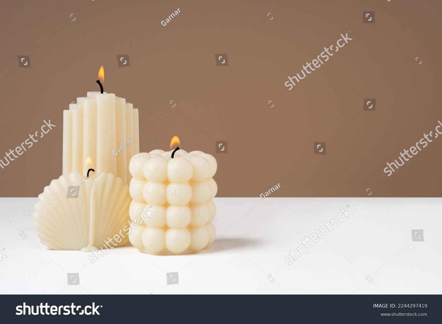 Handmade olive wax different forms burning candle on a duotone brown and white background. Sustainability vegan candle, natural materials. Minimalistic, cozy atmosphere modern photo.Copy space.Banner #2244297419