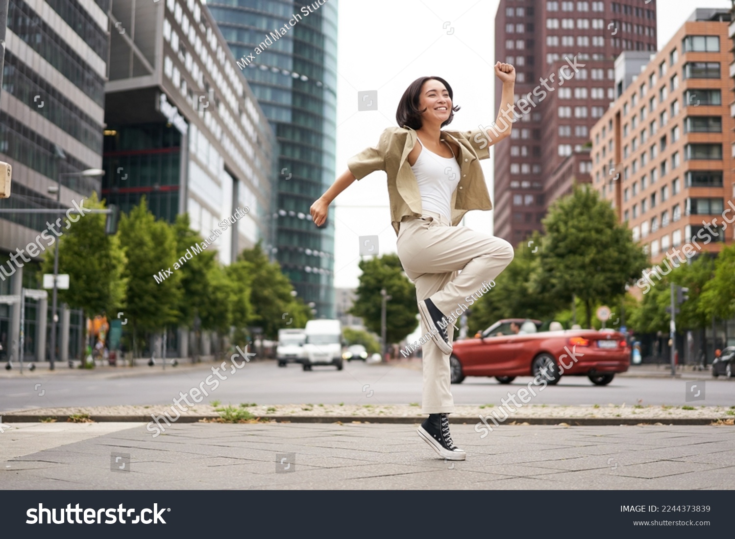 Portrait of asian happy girl jumping and dancing in city centre, posing on streets, express joy and excitement. Copy space #2244373839