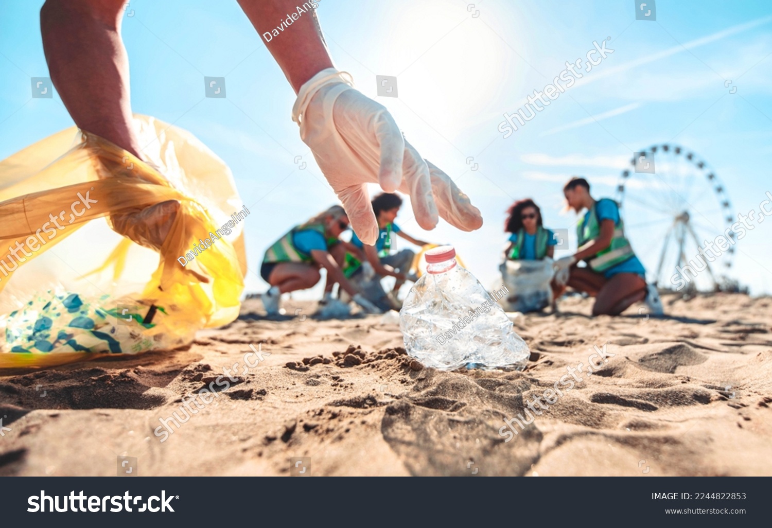 Group of eco volunteers picking up plastic trash on the beach - Activist people collecting garbage protecting the planet - Ocean pollution, environmental conservation and ecology concept #2244822853