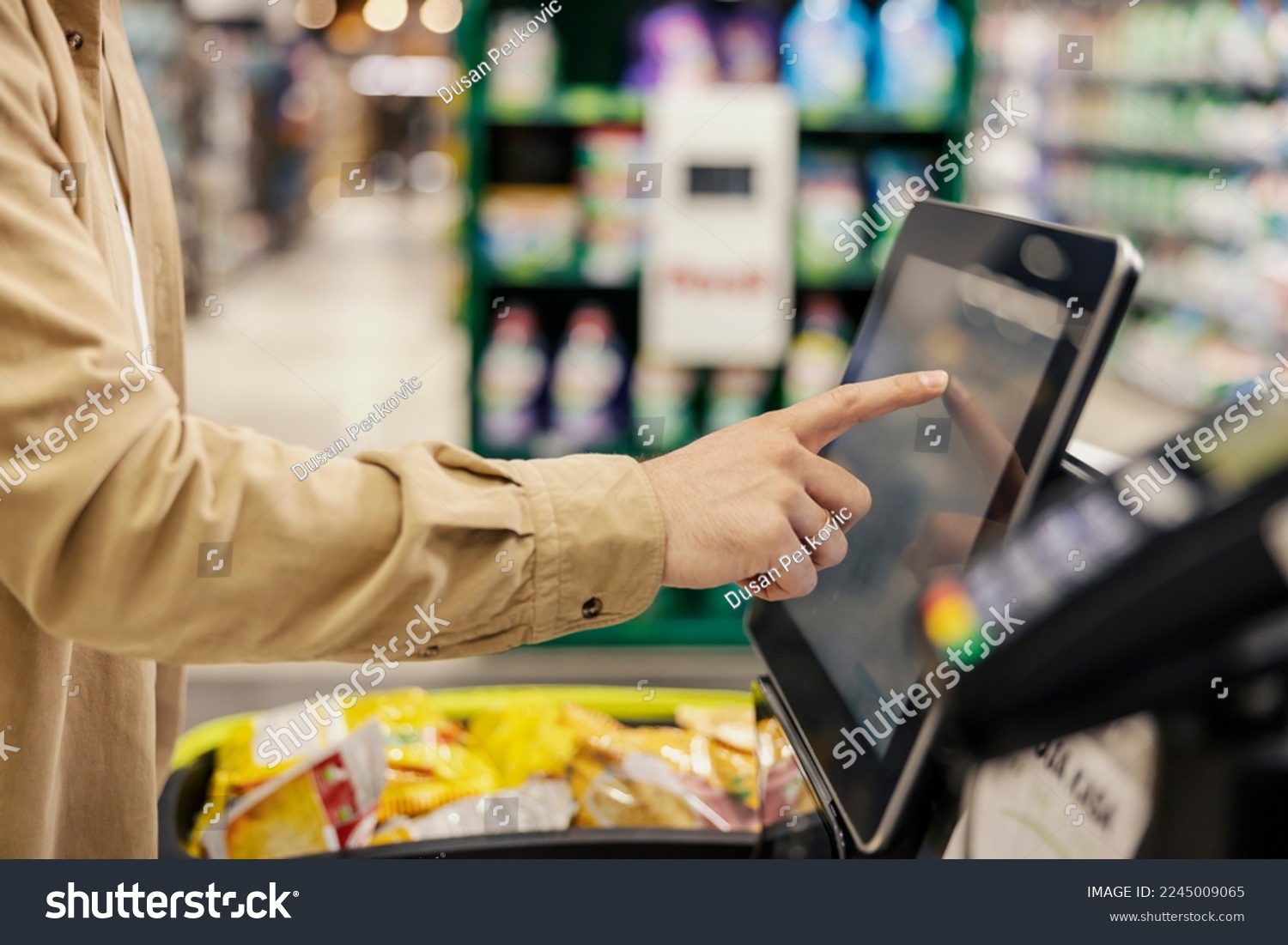 Hand of a man at self-service checkout in supermarket. #2245009065