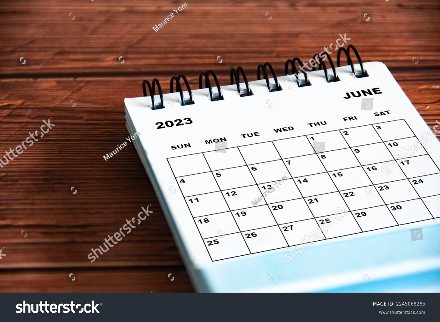 June 2023 white desk calendar on wooden table background. #2245068285