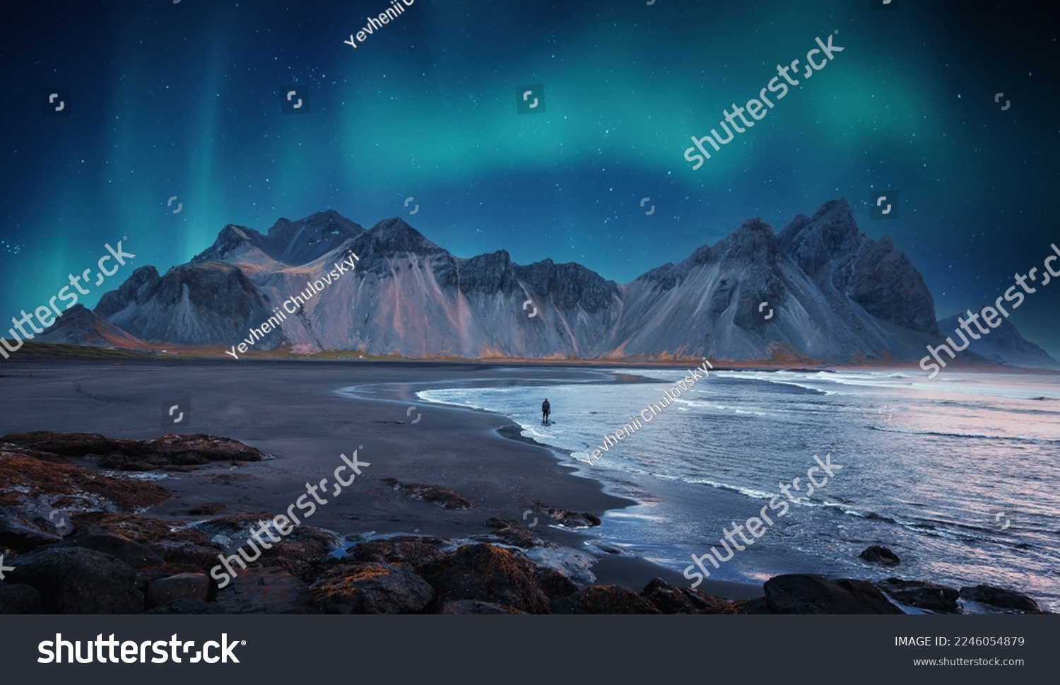 Incredible Iceland nature seascape. Iconic location for landscape photographers and bloggers. Scenic Image of Iceland. Alone tourist against Vestrahorn mountaine with Green northern lights #2246054879