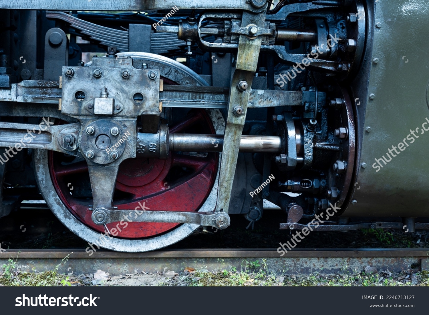 A close-up of a steam locomotive's propulsion system. Steam locomotive standing on the tracks, photo taken in natural lighting conditions. #2246713127
