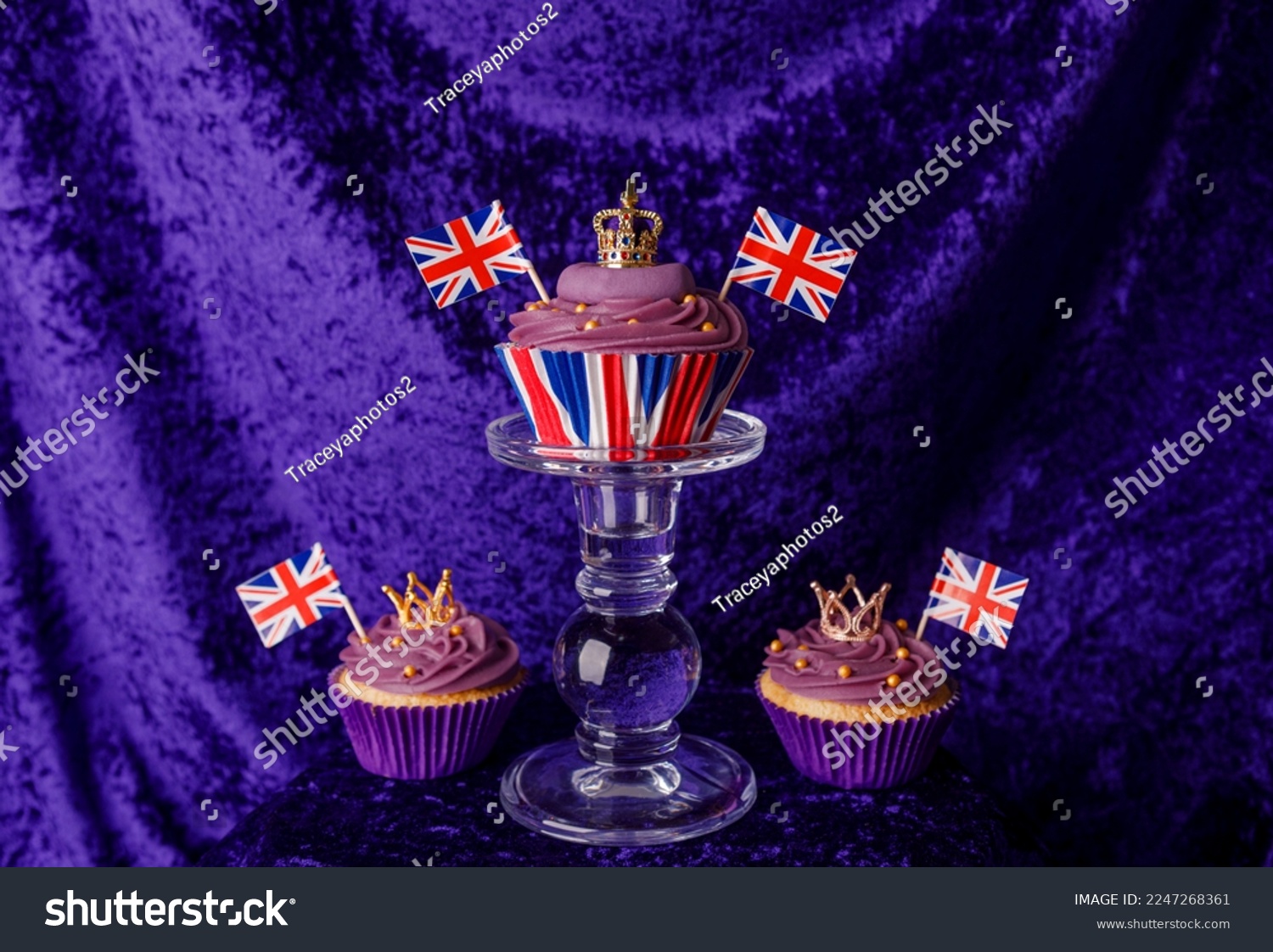 Royal Coronation Cupcakes to celebrate the coronation of King Charles III. Cupcakes decorated with the crown, purple velvet backdrop, union jacks flags, luxury cupcakes on a pedestal.  #2247268361