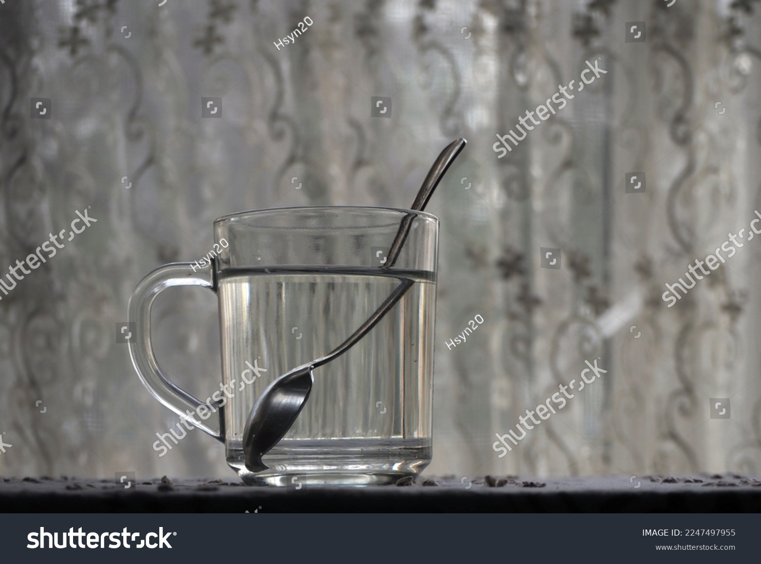 Refraction of the light. Tea spoon inside a glass of water, light refraction.       #2247497955