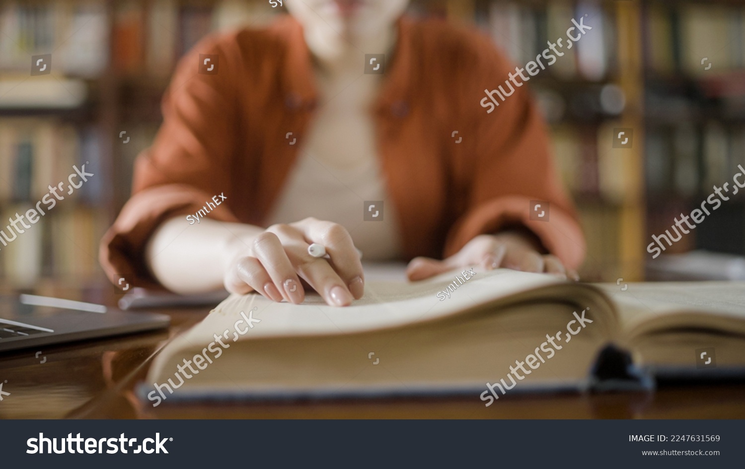 Woman doing research in a library, reading information in a large encyclopedia #2247631569